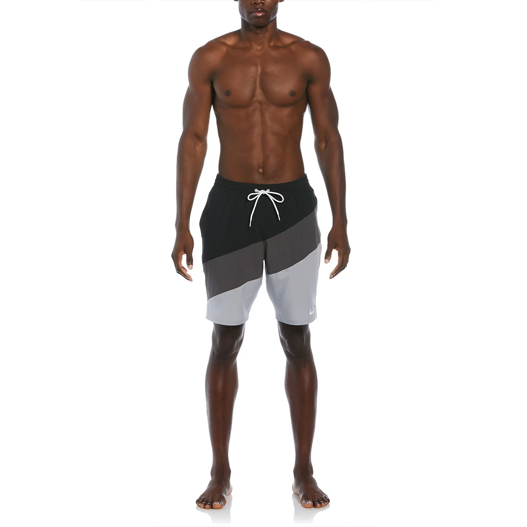 Man wearing black, gray, and white swim shorts on a white background