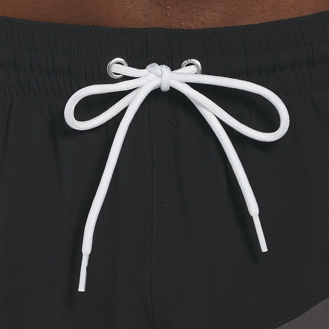 Close-up of black shorts with a white drawstring on a brown background